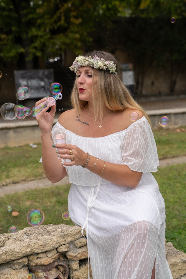 Future mariée en robe blanche et couronne de fleurs faisant des bulles de savon