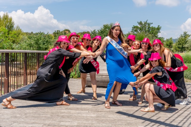 Groupe d'amies en casquettes roses posant autour de la future mariée