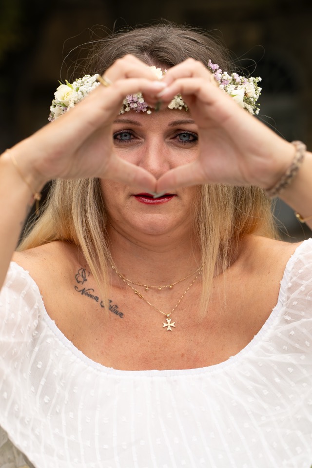 Future mariée formant un cœur avec ses mains, couronne de fleurs sur la tête
